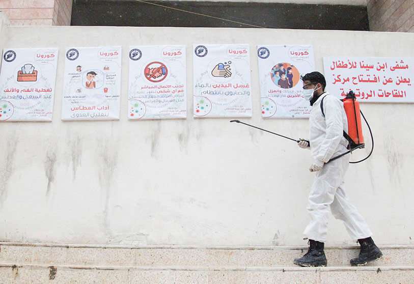 Un miembro de la ONG siria Violeta desinfecta la entrada del Hospital Ibn Sina en la ciudad de Idlib, al noroeste de Siria, el 19 de marzo de 2020
