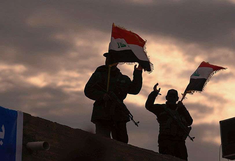 Miembros de las milicias apoyadas por Irán en Irak, conocidas como Fuerzas de Movilización Popular, agitan banderas iraquíes