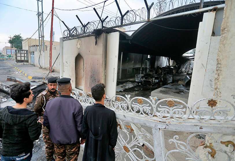 Fuerzas de seguridad y los civiles se reúnen cerca del quemado consulado iraní en Najaf, Irak, el jueves 28 de noviembre de 2019