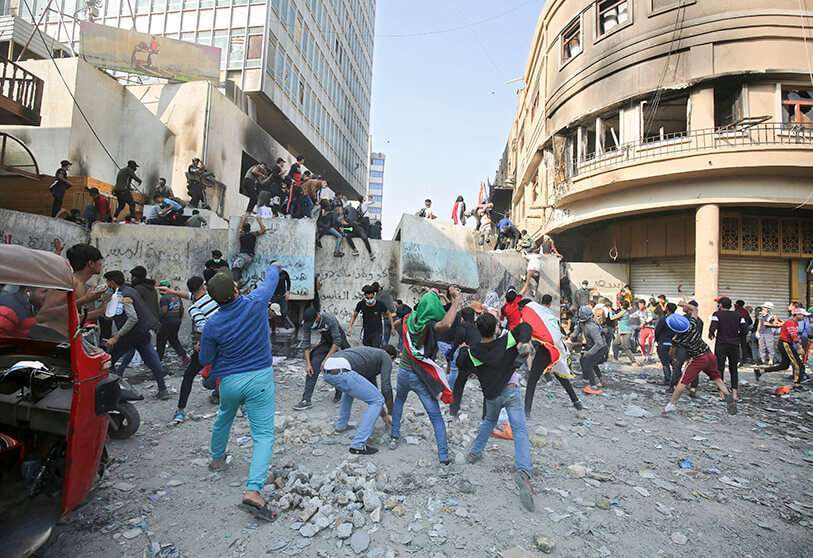 Manifestantes antigubernamentales lanzan piedras mientras las fuerzas de seguridad cierran la calle Rasheed durante los enfrentamientos en Bagdad, Irak, el miércoles 27 de noviembre de 2019