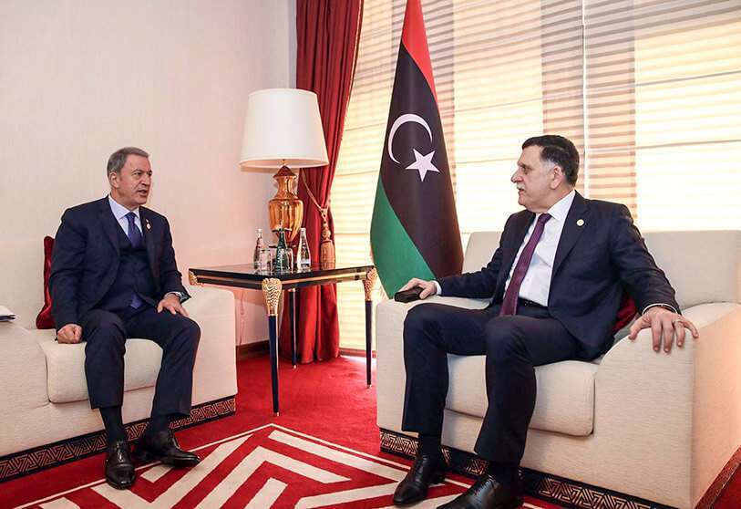 El Ministro de Defensa turco, Hulusi Akar (izq.), conversa con el Presidente del Consejo Presidencial de Libia, Fayez al-Sarraj, durante su reunión paralela al Foro de Doha de 2019.