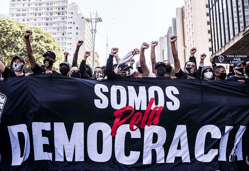 Los manifestantes gritan consignas y sostienen una pancarta durante una protesta antigubernamental en la Avenida Paulista