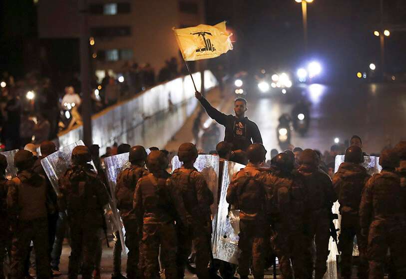 Un partidario del grupo militante de Hizbulá ondea la bandera de su grupo frente a soldados del Ejército libanés después de que estallara un enfrentamiento entre los manifestantes antigubernamentales y el grupo, en Beirut, Líbano, el lunes 25 de noviembre de 2019