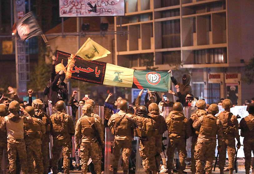 Los partidarios de los grupos chiíes libaneses Hizbulá y Amal ondean banderas y cantan delante de soldados del Ejército en Beirut, Líbano, el 25 de noviembre de 2019