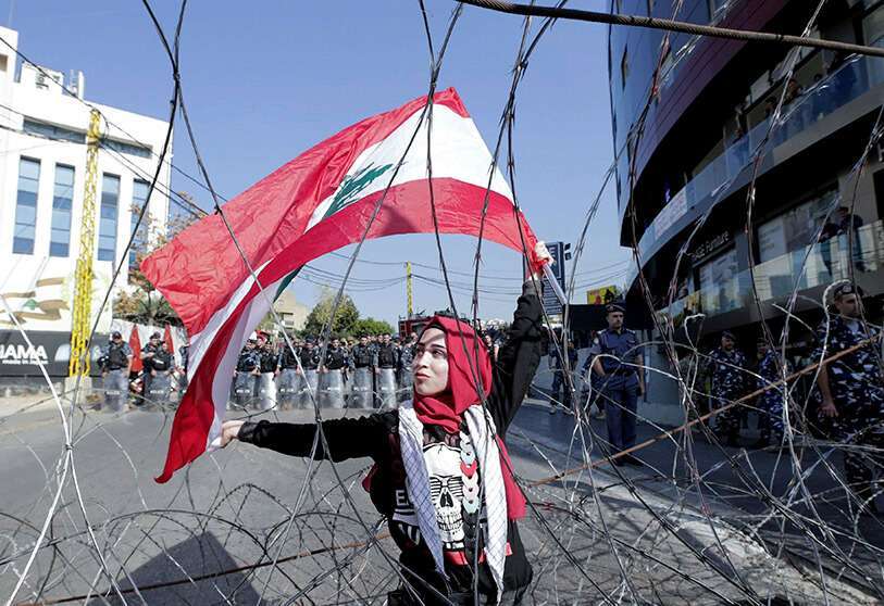 Una manifestante libanesa agita la bandera nacional mientras las fuerzas de seguridad se mantienen a la espera, durante una protesta cerca de la Embajada de Estados Unidos en Beirut, el 24 de noviembre de 2019