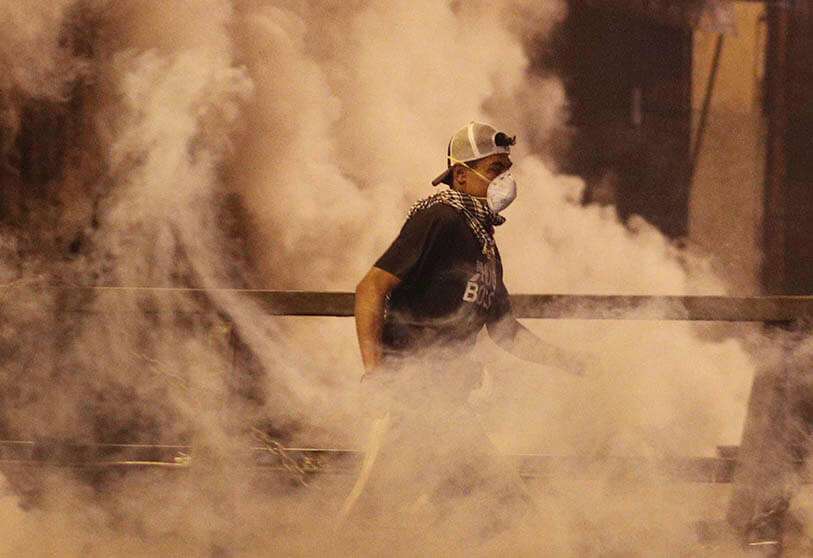 Un manifestante corre para cubrirse mientras la Policía lanza gas lacrimógeno durante una protesta contra la reelección del presidente Evo Morales, en La Paz, Bolivia, el jueves 7 de noviembre de 2019