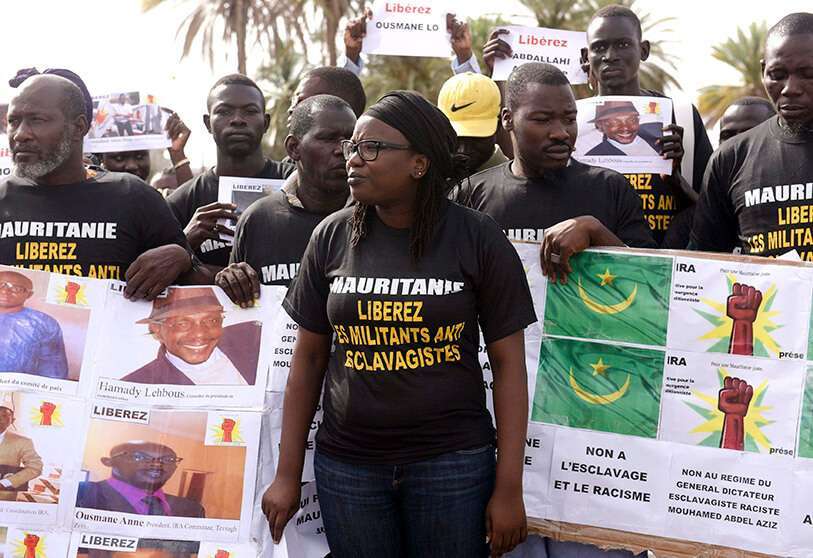 Los militantes antiesclavistas sostienen una pancarta que se traduce como "No a la esclavitud y al racismo, no al régimen del dictador general de la esclavitud, el racista Mouhamed Abdel Aziz" y se manifiestan el 3 de agosto de 2016 en Dakar contra el encarcelamiento de sus compañeros de lucha en Mauritania
