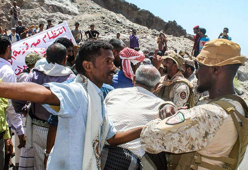 Un manifestante discute con un miembro de la seguridad de las fuerzas de la coalición respaldada por Arabia Saudí mientras los manifestantes se reúnen frente a la sede del Gobierno yemení reconocido internacionalmente en el Palacio de Al-Maashiq en el distrito de Crater de la ciudad portuaria del sur de Adén el 16 de marzo de 2021