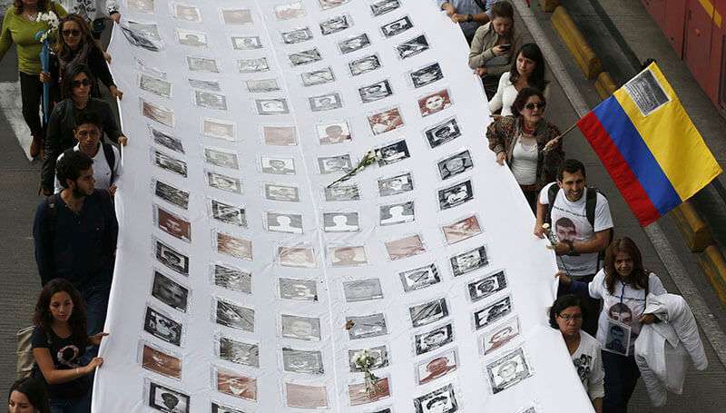 Manifestantes muestran fotos de víctimas de la violencia política de Colombia durante una marcha por la paz en Bogotá, Colombia, el miércoles 12 de octubre de 2016