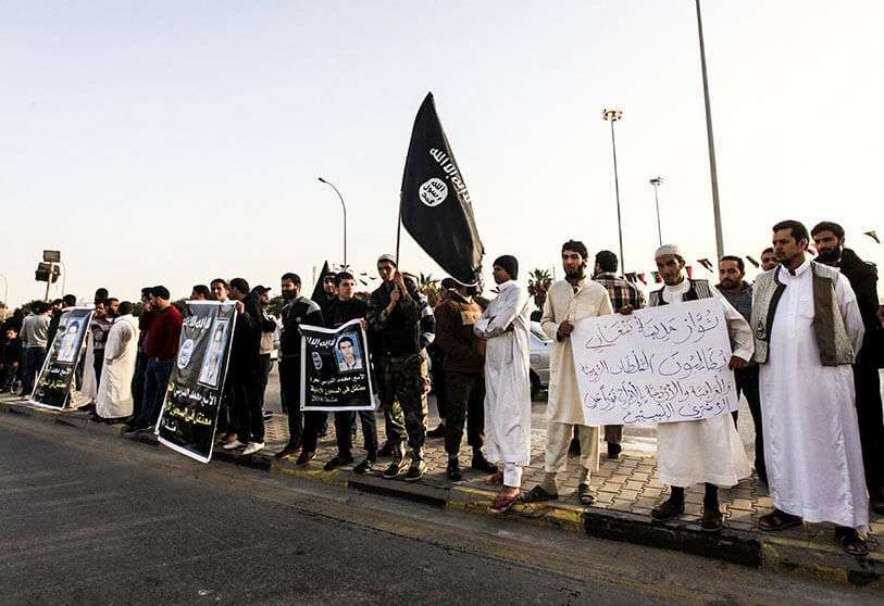 Manifestantes sostienen pancartas y la bandera salafista