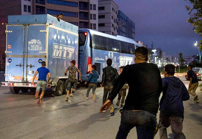 Jóvenes migrantes marroquíes sin hogar intentan viajar a Europa subiéndose a la parte trasera de un vehículo en la ciudad portuaria de Nador, en Marruecos, con la esperanza de encontrar un mejor nivel de vida