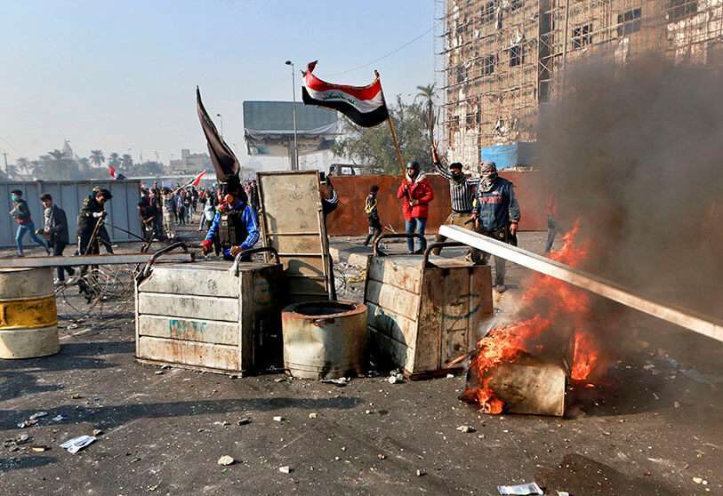 Manifestantes antigubernamentales cierran una calle mientras las fuerzas de seguridad utilizan gas lacrimógeno durante los enfrentamientos en el centro de Bagdad