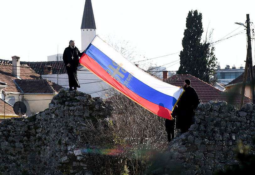 Un clérigo de la Iglesia Ortodoxa Serbia sostienen una bandera serbia cerca del Parlamento, antes de la votación de una polémica ley sobre la libertad religiosa en Podgorica