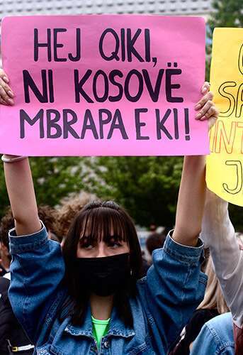 Chica sosteniendo el cartel donde se lee ‘Hej qiki, ni Kosovo mbrapa e ki’ (Eh chica, todo Kosovo está contigo)
