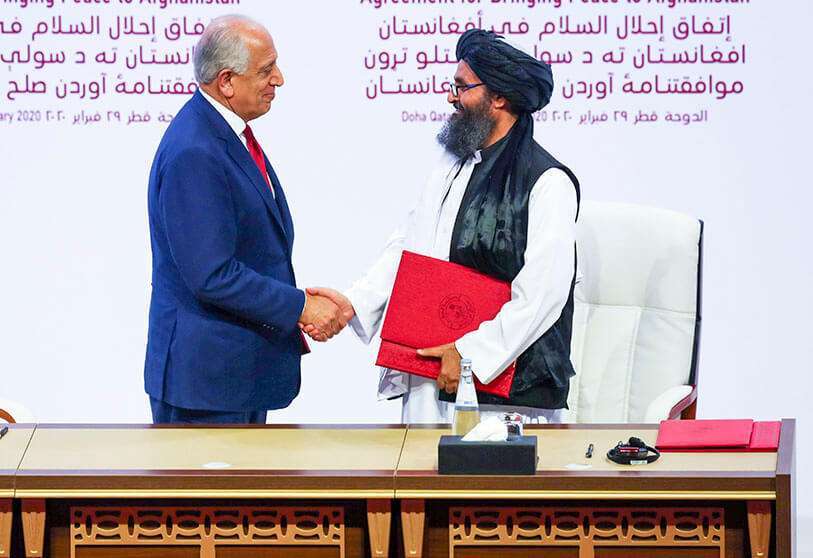 El mullah Abdul Ghani Baradar, líder de la delegación talibán, y Zalmay Khalilzad, enviado de Estados Unidos para la paz en Afganistán, se estrechan la mano en Doha, el 29 de febrero pasado