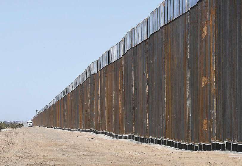 En esta foto de la mañana del martes 24 de marzo de 2020, un camión de cemento viaja en dirección este hacia el sitio de construcción de un nuevo "muro estilo bolardo" de 30 pies de alto en la proximidad de la calle 29 del condado y la avenida 6E al sur de Yuma, Ariz