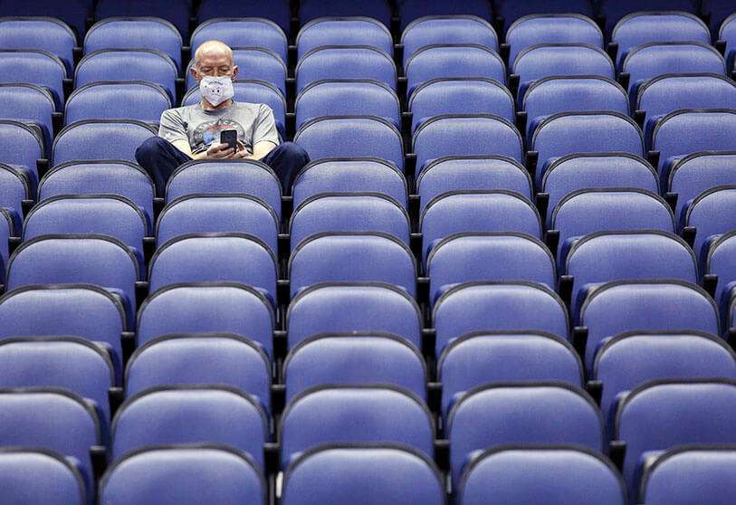 Un aficionado se sienta en un Coliseo de Greensboro vacío después de que los partidos de baloncesto universitario de la NCAA fueran cancelados