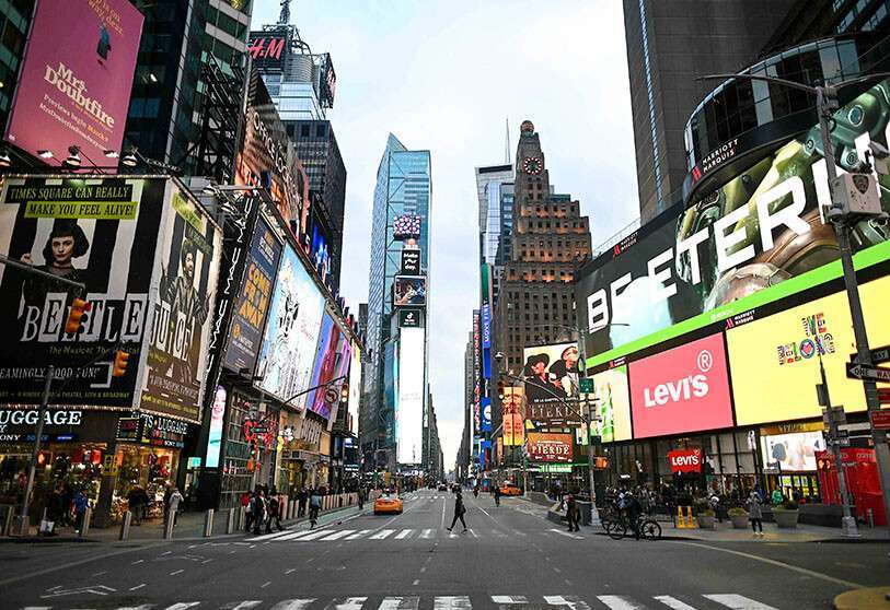 Una mujer con una máscara cruza la calle en Times Square en Manhattan, en la ciudad de Nueva York el 17 de marzo de 2020