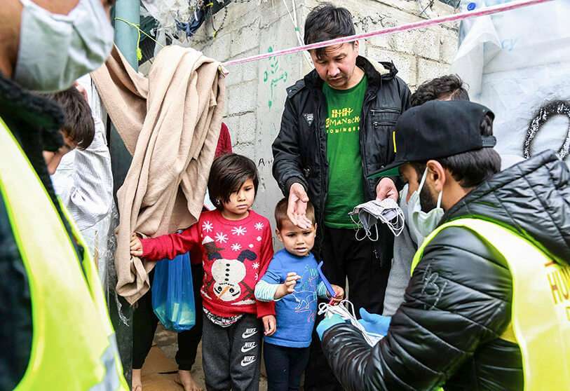 Miembros de la ONG “Team Humanity” comparten máscaras faciales de protección hechas a mano con migrantes y refugiados en el campamento de Moria en la isla de Lesbos, el 28 de marzo de 2020