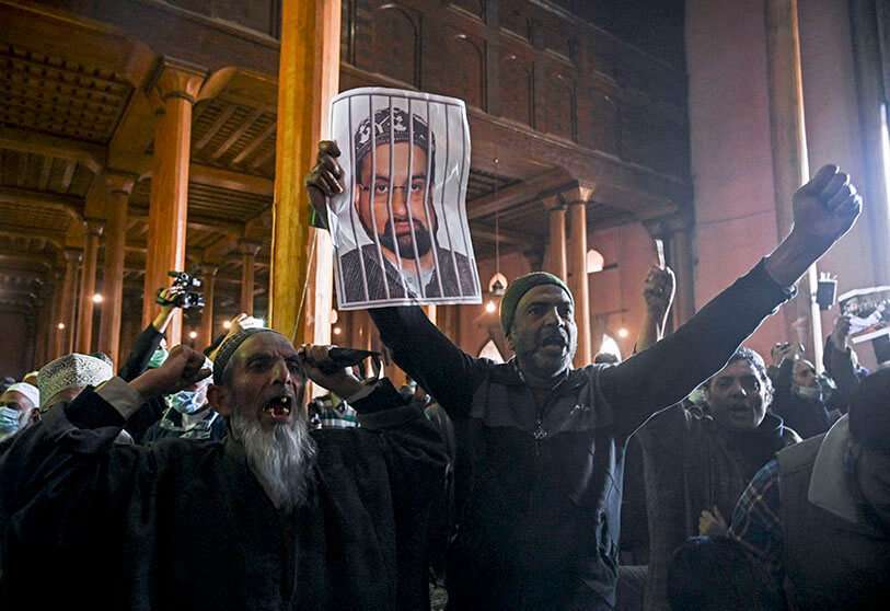 Un manifestante de Cachemira grita consignas y sostiene fotografías de Mirwaiz Umar Farooq, el clérigo principal de Cachemira que ha estado bajo arresto domiciliario durante 20 meses AFP/ TAUSEEF MUSTAFA