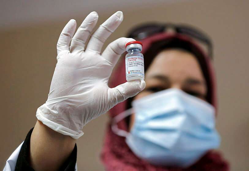 REUTERS/MUSSA QAWASMA - Un trabajador sanitario palestino sostiene un vial de la vacuna Moderna COVID-19 tras la entrega de dosis desde Israel, en Belén, en la Cisjordania ocupada por Israel