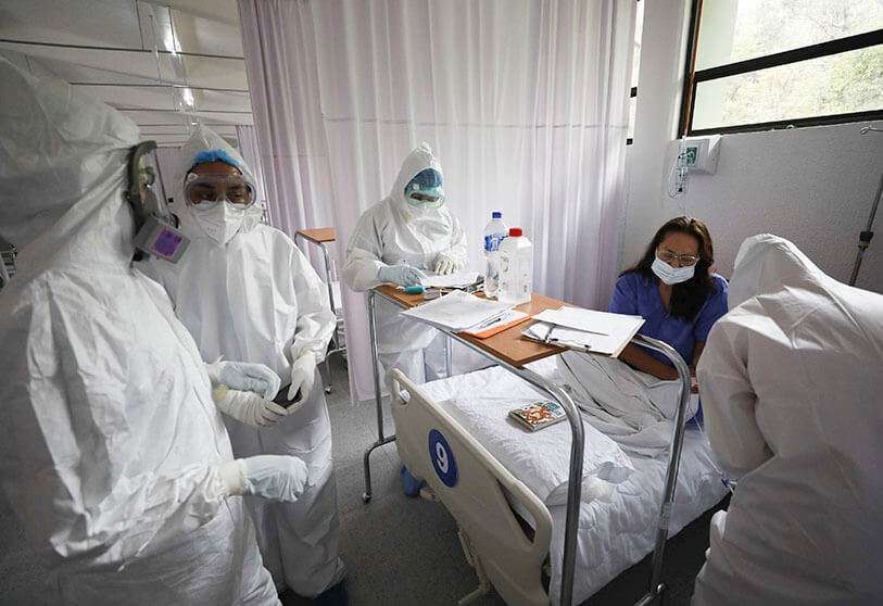 Personal médico con equipo de protección revisa a una paciente en la sala de mujeres de un hospital COVID-19 en el Campamento Militar 1, Naucalpan, Estado de México