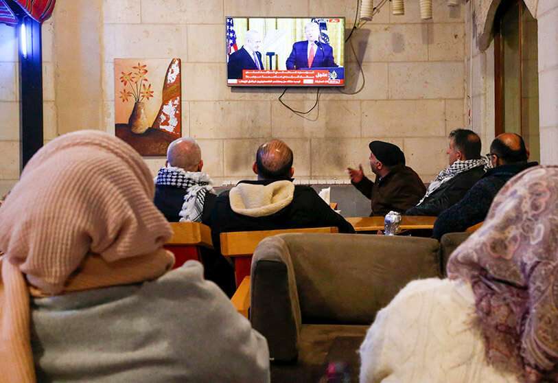 Palestinos ven la conferencia de prensa televisada del presidente de EEUU, Donald Trump, y el primer ministro israelí, Benjamin Netanyahu, el 28 de enero de 2020, en un café de la ciudad de Hebrón, en Cisjordania