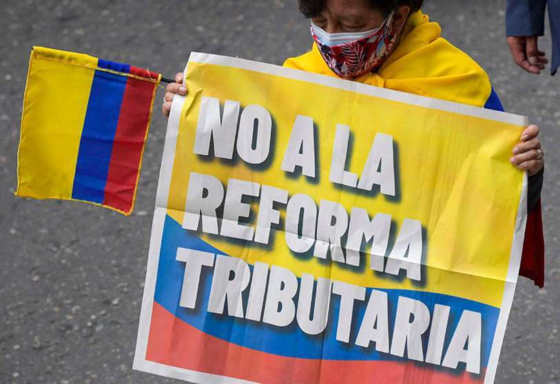 Una mujer sostiene un cartel que dice "No a la reforma tributaria" durante una manifestación contra la reforma tributaria propuesta por el presidente colombiano Iván Duque, en Bogotá, el 28 de abril de 2021