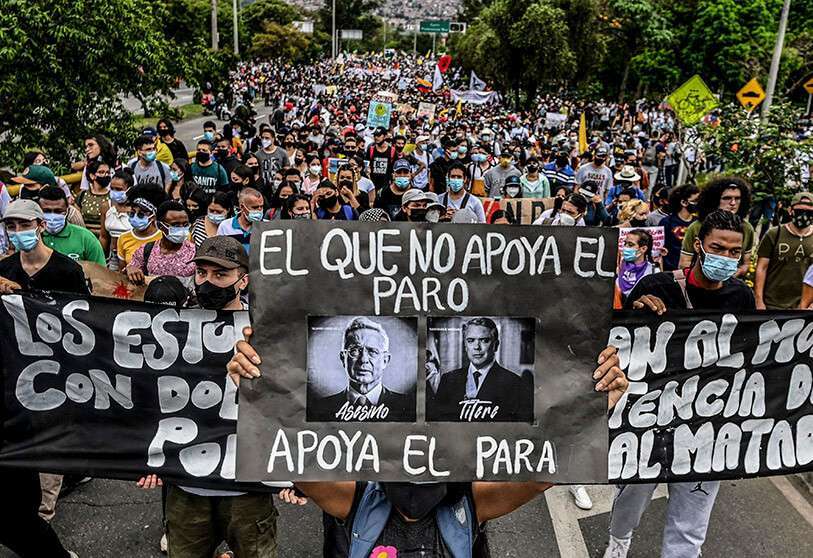Manifestantes sostienen un cartel con la imagen del expresidente colombiano (2002-2010) Álvaro Uribe y del actual presidente colombiano Iván Duque con la leyenda “El que no apoya el paro, apoya a los paramilitares”
