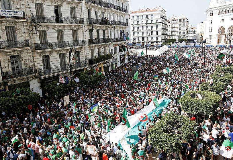 Manifestantes portan pancartas y banderas durante una protesta en la que se exige la destitución de la élite gobernante y el enjuiciamiento de antiguos funcionarios vinculados al ex presidente Abdelaziz Bouteflika, en Argel (Argelia) el 14 de junio de 2019