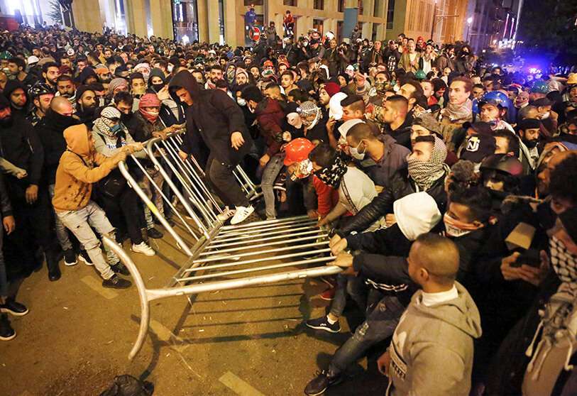 Manifestantes antigubernamentales quitan las vallas que estaban divididas entre ellos y la policía antidisturbios, durante una protesta cerca de la plaza del Parlamento, en el centro de Beirut, Líbano, el domingo 15 de diciembre de 2019