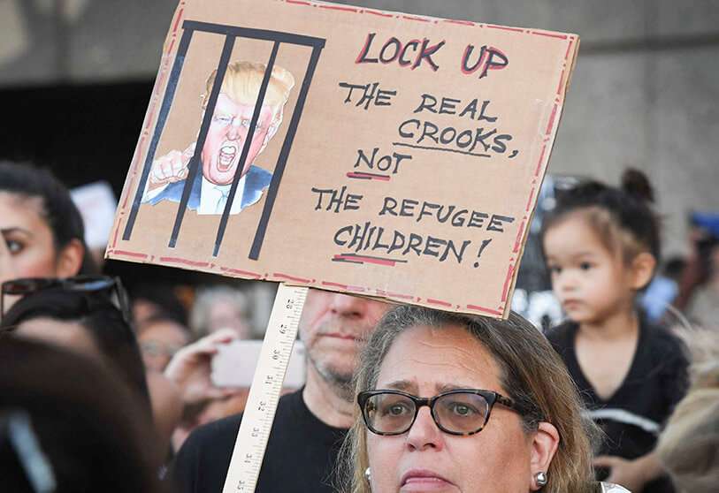 Una mujer protesta contra las próximas redadas y detenciones de solicitantes de asilo de ICE frente al principal centro de detención (de fondo) en el centro de Los Ángeles el 12 de julio de 2019