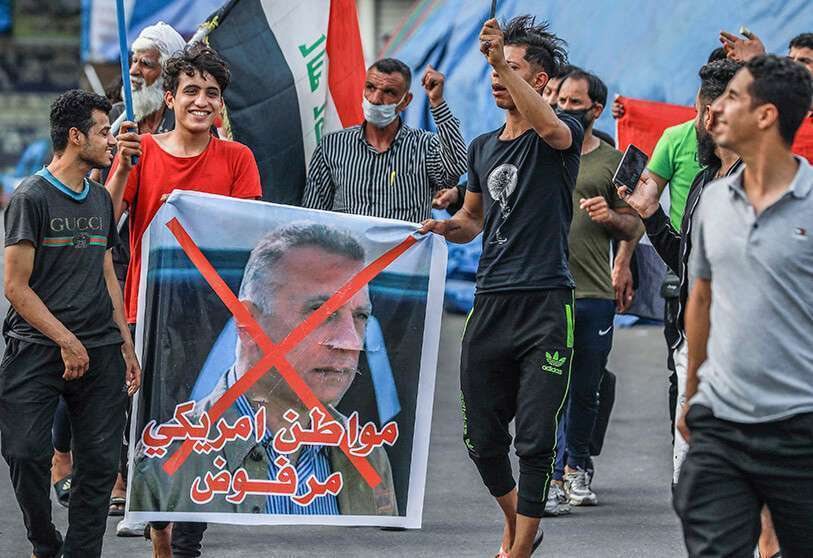 Manifestantes antigubernamentales sostienen una pancarta con una imagen desfigurada del nuevo primer ministro Al-Kadhimi, durante una manifestación contra su nombramiento en la plaza Tahrir
