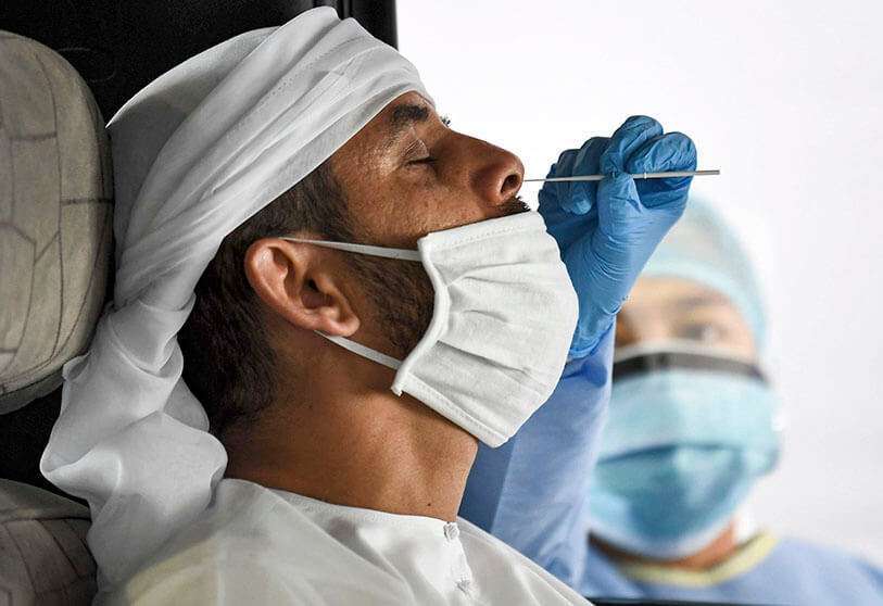 Un miembro del personal médico obtiene una muestra de hisopo de un hombre dentro de un vehículo en un centro de pruebas de coronavirus COVID-19 en Emiratos Árabes Unidos