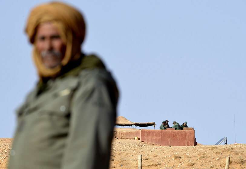 Una foto de archivo tomada el 3 de febrero de 2017 de un hombre saharaui de pie en la zona de Al-Mahbes, cerca de soldados marroquíes que custodian el muro que separa el Sáhara Occidental controlado por el Polisario