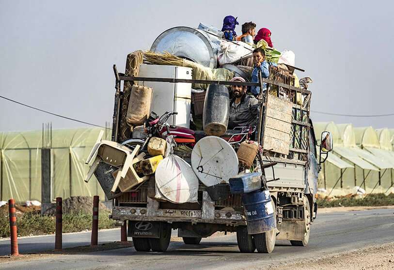 Los sirios huyen con sus pertenencias del campo de la ciudad siria de Ras al-Ain, al noreste de Siria, el 19 de octubre de 2019