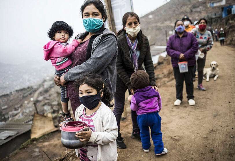 Residentes con máscaras para frenar la propagación del nuevo coronavirus esperan en una fila para una comida gratis en el distrito de Villa María del Triunfo en Lima, Perú, el miércoles 17 de junio de 2020