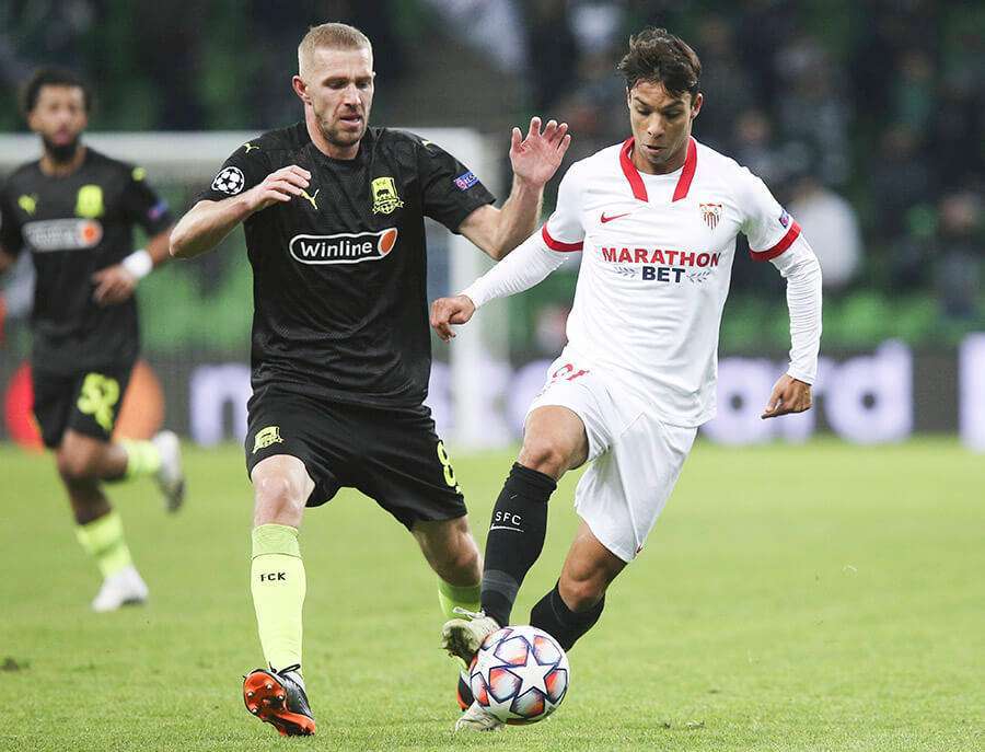 El sevillista Oliver Torres, izquierda, compite por el balón con Yury Gazinsky de Krasnodar durante el partido de fútbol del grupo E de la Liga de Campeones de la UEFA, entre Krasnodar y Sevilla en el estadio de Krasnodar, Rusia, el martes 24 de noviembre de 2020