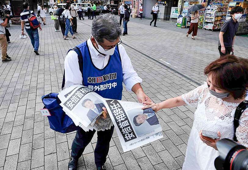El personal de ventas de una empresa de periódicos locales da ediciones extras a la gente para informar de la renuncia del primer ministro Abe, en Tokio, el 28 de agosto de 2020