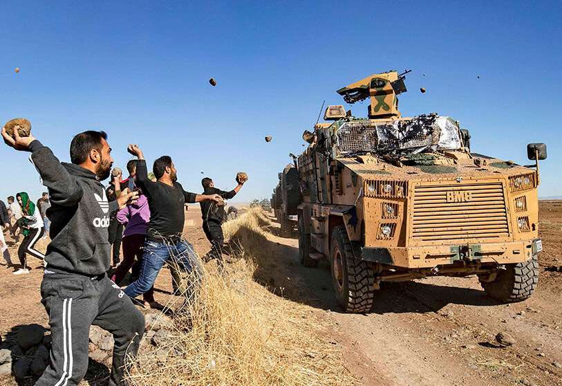 Manifestantes kurdos lanzan piedras contra un vehículo militar turco el 8 de noviembre de 2019, durante una patrulla conjunta turco-rusa cerca de la ciudad de Al-Muabbadah, en la parte noreste de Hassakah, en la frontera siria con Turquía