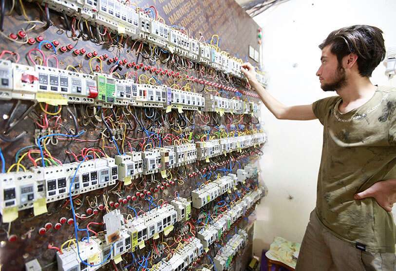 Un trabajador con un tablero de un generador eléctrico, en Najaf, Irak
