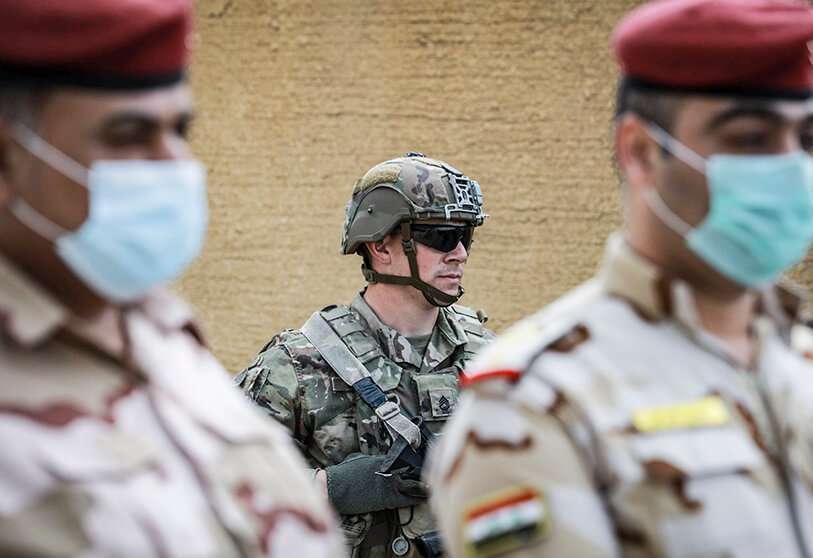 Un soldado estadounidense está detrás de los soldados iraquíes con máscaras durante la ceremonia de entrega de la Base Aérea K1 cerca de Kirkuk en el norte de Irak