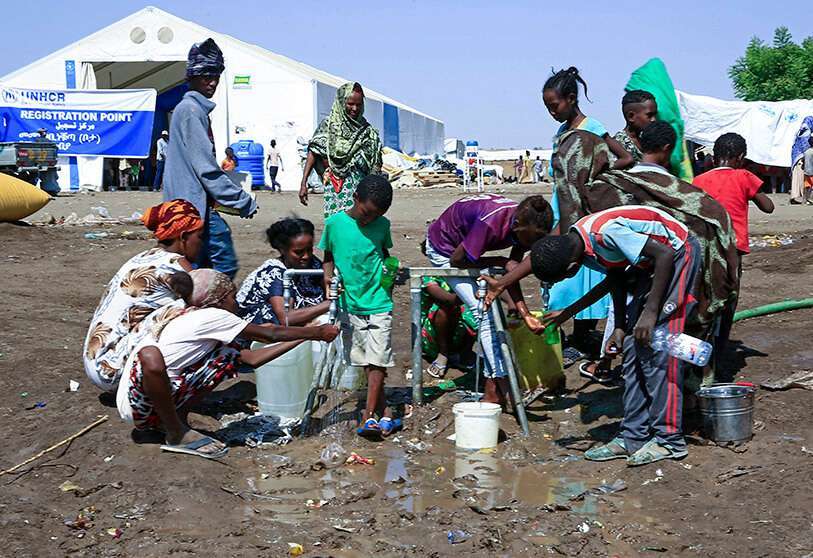 Refugiados etíopes que han huido del conflicto de Tigray, llenan botellas y recipientes con agua tras llegar a un centro de tránsito en la ciudad fronteriza sudanesa de Hamdayit el 27 de noviembre de 2020. AFP/ ASHRAF SHAZLY