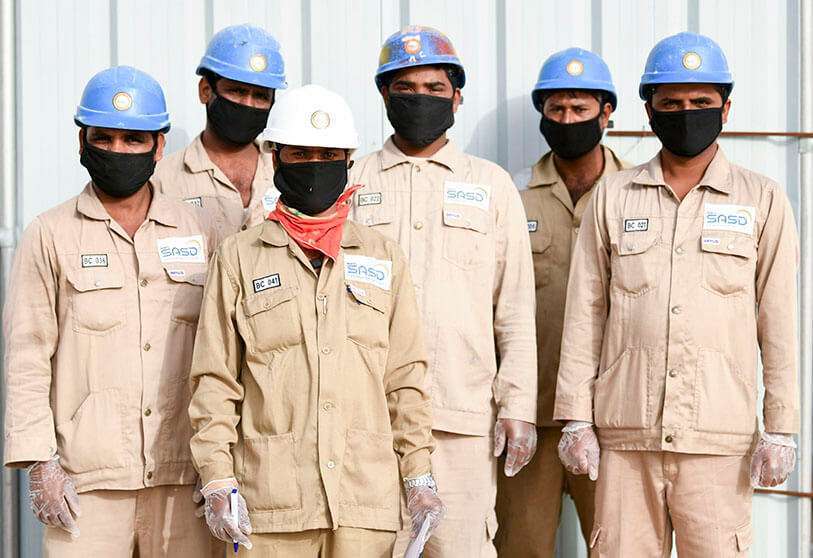 Trabajadores indios de una empresa de servicios públicos en los Emiratos Árabes Unidos, con su equipo de protección, máscaras y guantes, durante la pandemia del coronavirus COVID-19