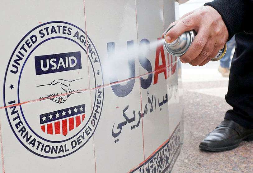 Un hombre palestino rocía pintura para cubrir un logotipo de la Agencia de los Estados Unidos para el Desarrollo Internacional (USAID), el 4 de febrero de 2020