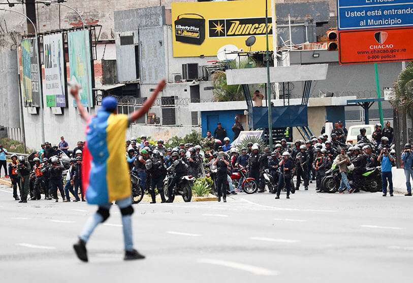 Un manifestante cubierto con una bandera venezolana frente a las fuerzas de seguridad durante una protesta en Caracas, Venezuela, el 10 de marzo de 2020