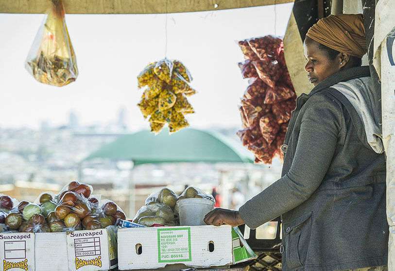 Un vendedor ambulante sudafricano espera a los clientes en el municipio de Alexandra, en el telón de fondo de las Torres Sandton, uno de los principales y más prestigiosos centros comerciales de África, el 26 de agosto de 2014 en Johannesburgo (Sudáfrica)