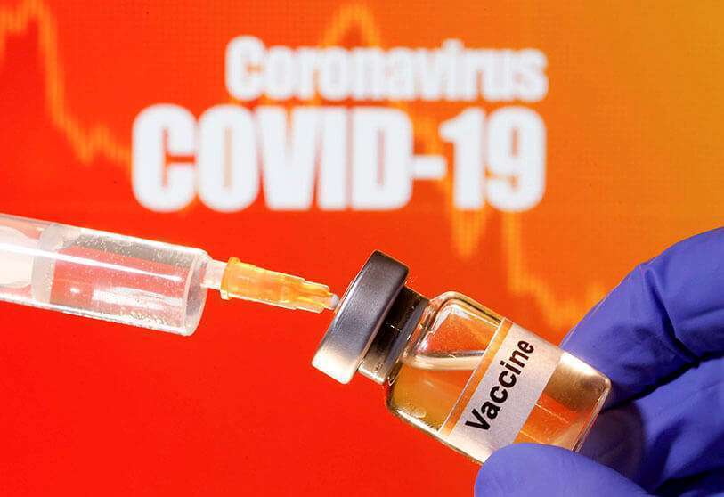 Un pequeño frasco etiquetado se sostiene cerca de una jeringa médica