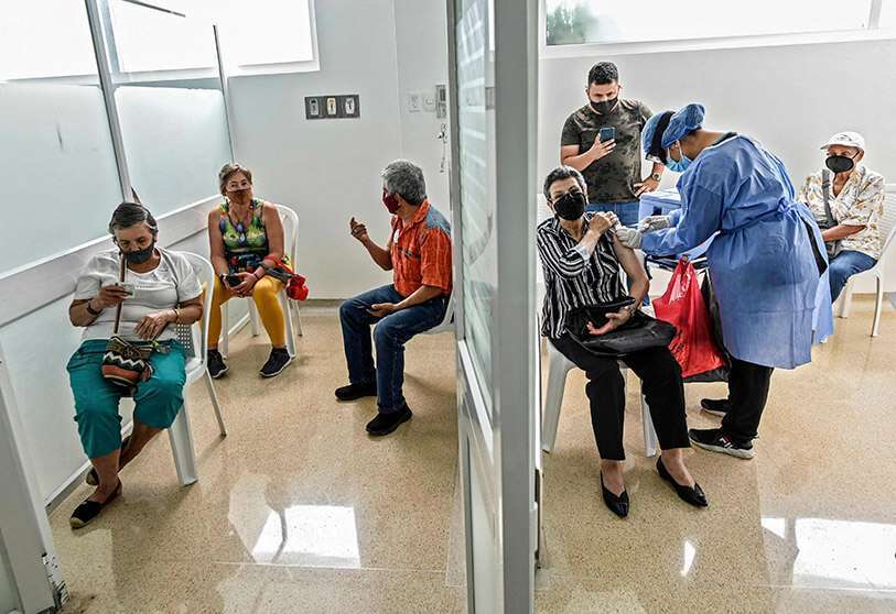 Una mujer recibe la vacuna Oxford/AstraZeneca contra la COVID-19 en un centro de vacunación, mientras otras personas esperan, en medio de la nueva pandemia de coronavirus, en Medellín, Colombia, el 7 de abril de 2021 AFP/JOAQUIN SARMIENTO