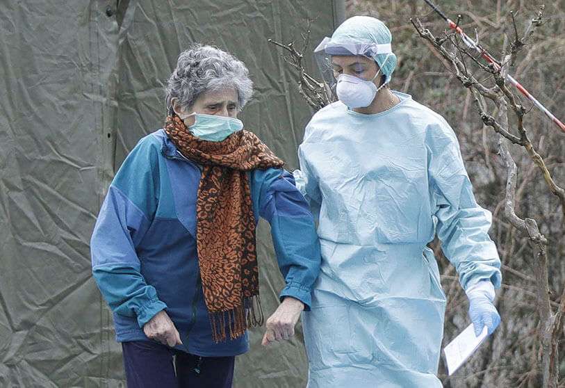 Un paciente anciano es ayudado por un médico en una de las estructuras de emergencia creadas para facilitar los procedimientos en el hospital de Brescia, en el norte de Italia
